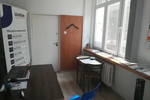 Biuro Unilink z banerem informacyjnym, biurkiem z laptopem i oknem.