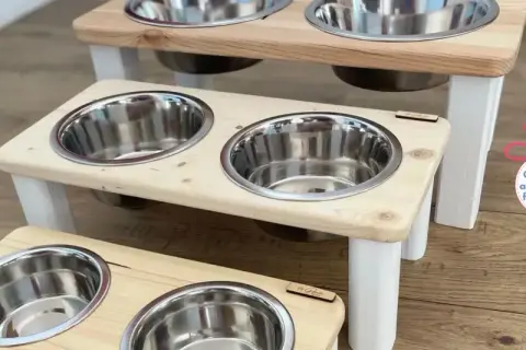 Trois gamelles pour chien en bois, sur pieds blancs, avec bols en inox. Une création artisanale française pour le repas de votre compagnon.