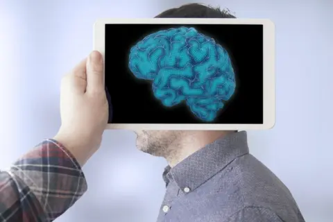 Dłoń trzyma tablet z cyfrowym mózgiem, sugerując analizę poziomów IQ.