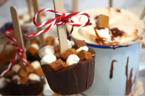 Chokladkoppar med marshmallows och kola, redo att smältas ner i varm choklad. En härlig juldekoration.