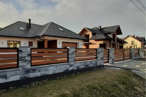 Nowoczesne ogrodzenia domów z kamienia i drewna, otaczające biały i budowany dom.