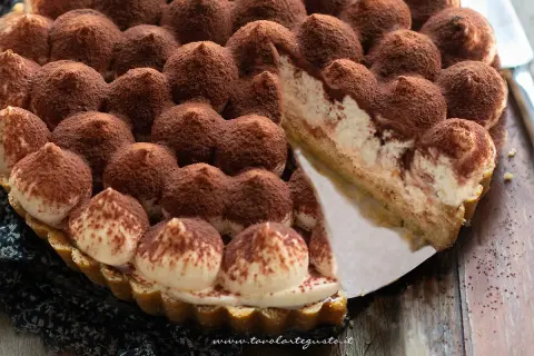 Una deliziosa torta tiramisù, con ciuffi di crema e cacao, pronta per essere gustata.