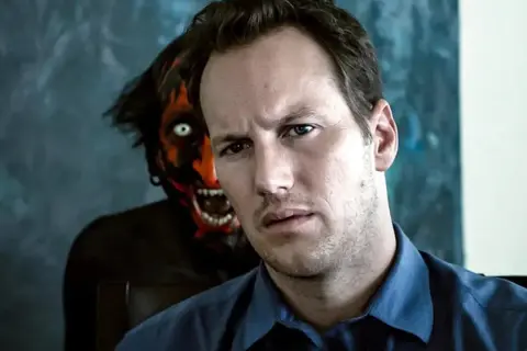 Mężczyzna z przerażeniem patrzy w obiektyw, podczas gdy za nim czai się demon. Scena jak z najlepszych filmów grozy.