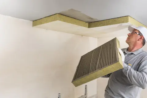 Mann montiert Dämmplatten zur Deckenisolierung innen.