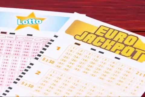 Kupony Lotto i Eurojackpot, do której wysyłamy eurojackpot, leżą na drewnianym stole.