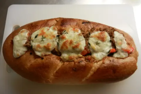 En gyllene, fylld fransk baguette med smält ost och örter.