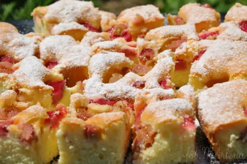 Puszyste ciasto z rabarbarem, posypane cukrem pudrem. Idealne na letnie popołudnie, gdy masz ochotę na domowy **przepis na ciasto z rabarbarem**.