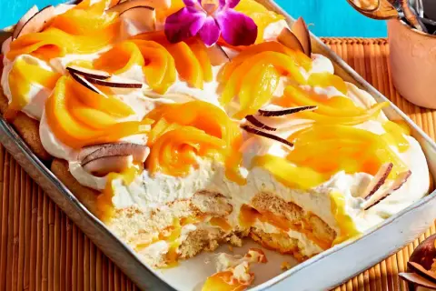Ein cremiges Mango Tiramisu mit Kokosflocken und einer exotischen Orchidee verziert.