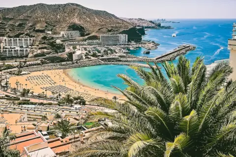 Gran Canaria w czerwcu: słoneczna plaża, turkusowe morze i palmy. Idealna pogoda na wakacje.