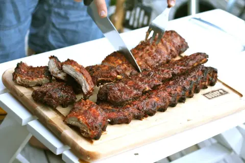 Grillade kamben skärs upp på en skärbräda. Saftiga och rökiga, redo att avnjutas.