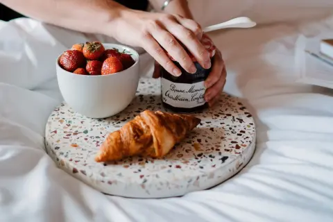 Een croissant, aardbeien en confituur op een dienblad. Perfect om te genieten van eten uit verveling op een luie ochtend.