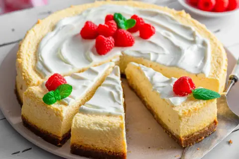 Ein köstlicher american cheesecake, dekoriert mit frischen Himbeeren und Minze, wartet darauf, genossen zu werden.