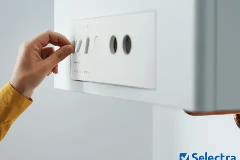 Main d'une personne ajustant le bouton d'une prime cee chaudière gaz.