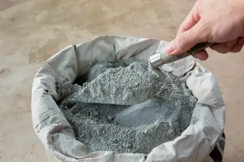 Łopata nabiera suchy beton z worka. Kluczowe są właściwe proporcje do uzyskania mocnej mieszanki.