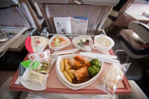 Ein Flugzeugessen mit Hähnchen, Kartoffeln, Brokkoli, Salat und einem Dessert. Guten Appetit beim Essen im Flugzeug!