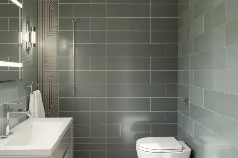 Salle de bain moderne avec lavabo, miroir éclairé et WC. Le carrelage sur placo gris et vert crée une ambiance épurée.