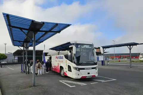 Autobus Aerobus z napisem "Paris-Beauvais" czeka na pasażerów pod niebieskim zadaszeniem.