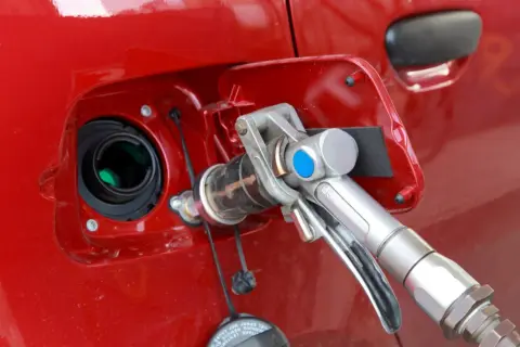 Remplissage d'une voiture rouge avec un pistolet GPL. Avis sur la bicarburation essence/GPL.