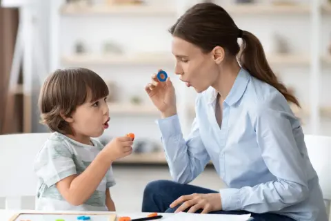 Terapeuta enseña trabalenguas para niños usando piezas de letras.
