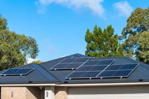Pannelli solari sul tetto di una casa, con alberi sullo sfondo. Si valuta il collegamento pannelli solari in serie o parallelo per massimizzare l'energia.