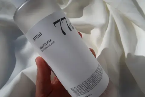 Anua Heartleaf Soothing Toner 77% w dłoni na tle białej tkaniny. Idealny do codziennej pielęgnacji.