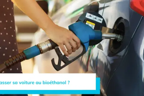 Main d'une personne tenant un pistolet de pompe à essence pour faire le plein d'une voiture. Recherche d'une liste voiture compatible e85 sans kit pour rouler plus vert.