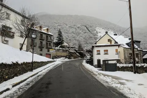 Un pueblo nevado, ideal para un fin de semana en Jaca. Casas de piedra y tejados blancos bajo un cielo gris.
