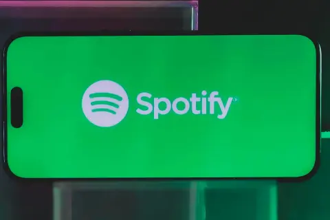 A smartphone displays the Spotify logo on a vibrant green screen, hinting at a free distributor for Spotify.