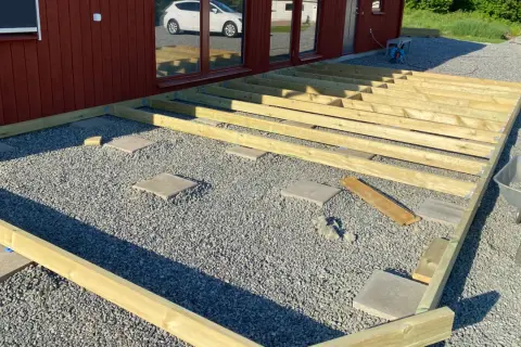 Bygga altan på plattor. Träkonstruktion för altan monteras på grusunderlag med stenplattor som stöd.