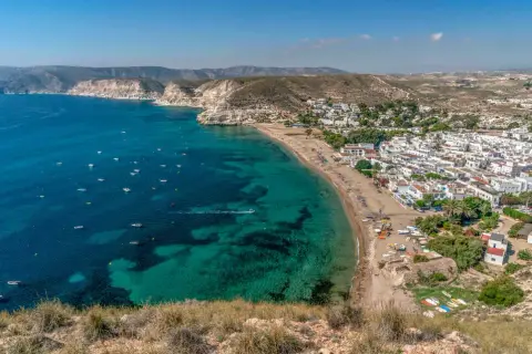 Vista aérea de la costa con aguas turquesas, barcos y el pueblo blanco de restaurante costamarga.