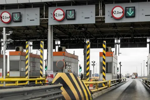 Płatne autostrady w Polsce: szlabany na bramkach poboru opłat, znaki ograniczenia wysokości 2,0m i zielone strzałki wskazujące otwarte pasy ruchu.