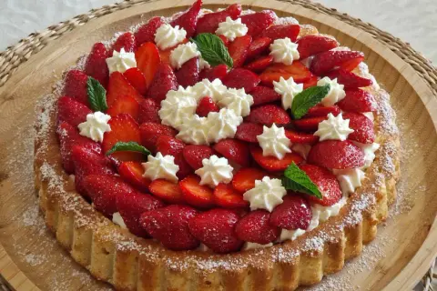 Un délicieux biscuit pour fraisier, garni de fraises fraîches, de crème fouettée et de feuilles de menthe.