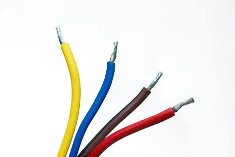 Quatre fils électriques dénudés : un jaune, un bleu, un fil bleu et marron, et un rouge, sur fond blanc.