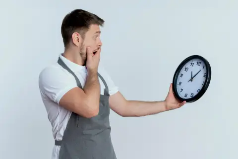 Zaskoczony mężczyzna w fartuchu patrzy na zegarek. Czyżby czekały go nadgodziny w Niemczech?