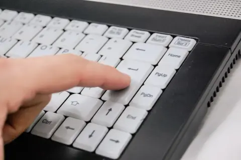 Palec naciska klawisz Enter na klawiaturze ultrabooka. Co to jest ultrabook? To lekki i cienki laptop.