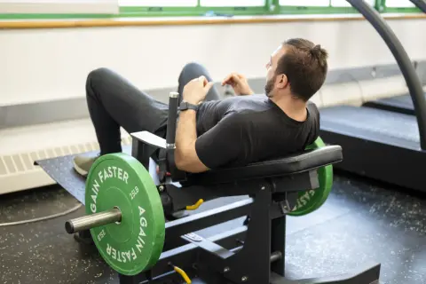 Man tränar höfterna på en hip thrust maskin med viktskivor.
