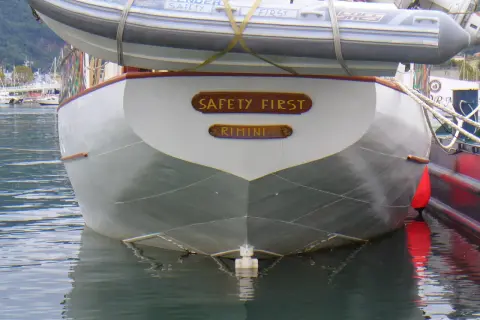 La poppa di una barca con la scritta "SAFETY FIRST RIMINI". Il suo mascone, simbolo di sicurezza, è ben visibile.