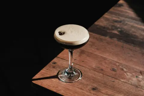 Elegancki kieliszek z pianką, ozdobiony ziarnem kawy, idealny do delektowania się drinkiem espresso martini.