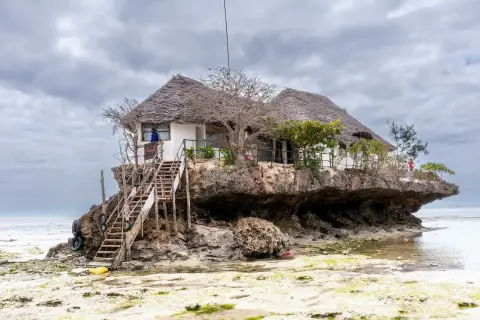 Wyjątkowy dom na skale, idealne miejsce na zanzibar wakacje. Drewniane schody prowadzą do restauracji z trawiastym dachem.