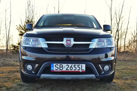 Czarny Fiat Freemont na tle drzew. Zastanawiasz się nad jego spalaniem? Ten SUV oferuje przestronne wnętrze i komfort podróżowania.