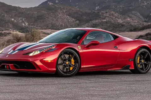 Czerwone Ferrari 458 z białymi i niebieskimi pasami na masce, zaparkowane na tle górskiego krajobrazu.