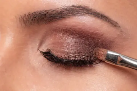 Aplicando sombra marrón con brocha. Aprende como maquillar los ojos a partir de los 50 años para un look elegante y natural.