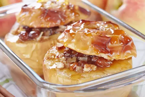 Deux pommes au four dorées, garnies de noix et de raisins secs, nappées d'un sirop brillant. Un délice réconfortant.