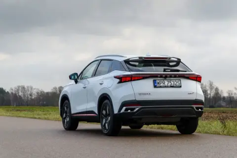 Biały, nowoczesny SUV OMODA S z charakterystycznym pasem świateł z tyłu. To jeden z nowych chińskich samochodów, który zyskuje popularność.