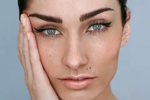 Mujer con microblading cejas perfectas, delineado de ojos y piel radiante.