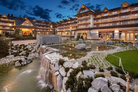 Elegancki hotel spa w górach z kaskadą wodną i stawem.