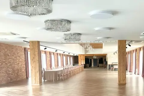Elegancka sala weselna z kryształowymi żyrandolami i długim stołem. Zastanawiasz się, ile pieniędzy na ślub?