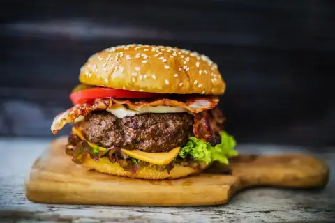 Soczysty burger z bekonem, serem i warzywami. Idealny przykład, jak przyprawić mięso na hamburgery, by uzyskać wyśmienity smak.