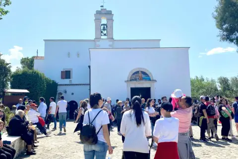 Folla di fedeli davanti alla chiesa di Santa Maria di Merino, con il campanile e un mosaico sopra l'ingresso.