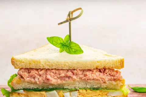 Tramezzini veloci con tonno, uova e lattuga, guarniti con basilico fresco. Perfetti per un pasto rapido e gustoso.